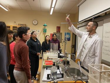 Students watch as teacher demonstrates a chemistry lab