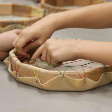 Students hands and Staff hand working together to make drum