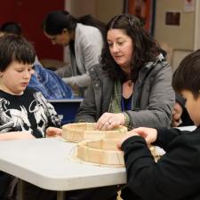 Principal sitting with students, working on making drums