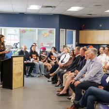 Female student stands at podium in front of audience, speaking about the project